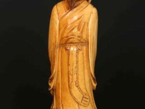 A CHINESE STAINED IVORY FIGURE, 19th Century, carved as an elder in flowing...