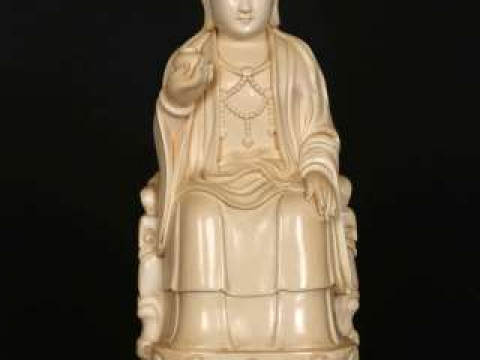 A CHINESE IVORY FIGURE, late 19th/early 20th Century, carved as a seated...