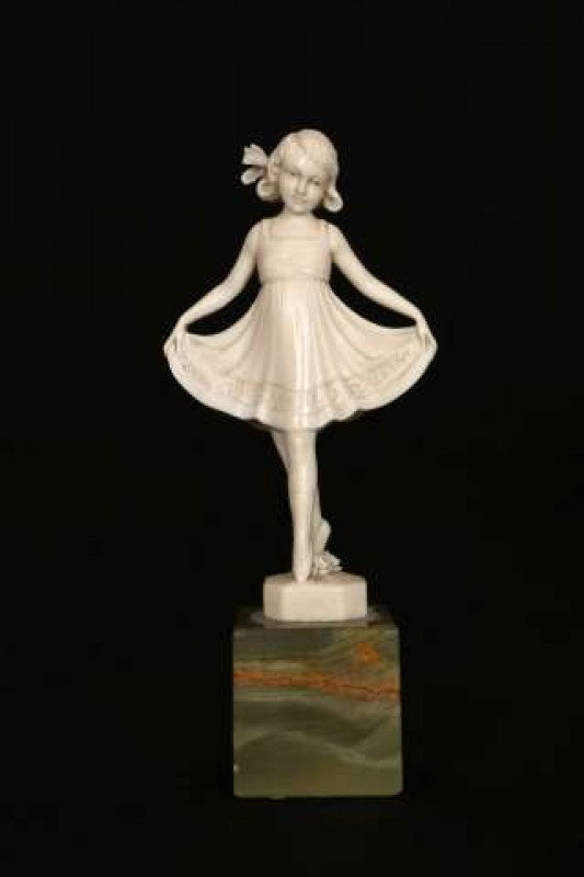 A FINELY CARVED IVORY FIGURE OF A TYROLEAN GIRL, c. 1930's, in the manner of Ferdinand Preiss, carved holding the edges of her dress, raised on an onyx plinth, unsigned. Ivory 9cm, overall 12cm