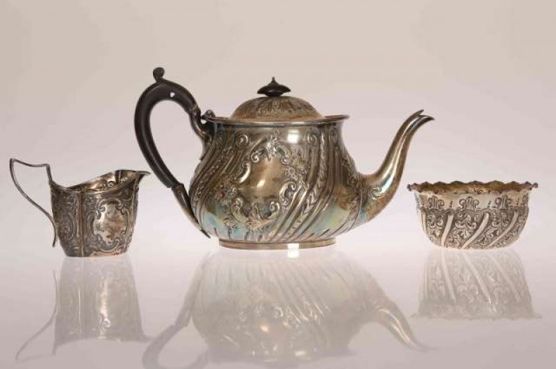 A VICTORIAN SILVER TEAPOT, Martin Hall & Co, Sheffield 1893, chased with scrolls and foliage; together with A SILVER CREAM JUG, Birmingham 1895, similarly chased; and A SILVER SUGAR BOWL, London 1895. (3) Gross 26oz