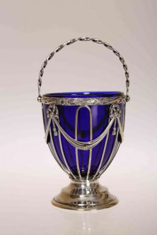AN EDWARDIAN SILVER SUGAR BASKET, Haseler Brothers, Chester 1908, with swing handle and blue glass liner. 9cm excluding handle