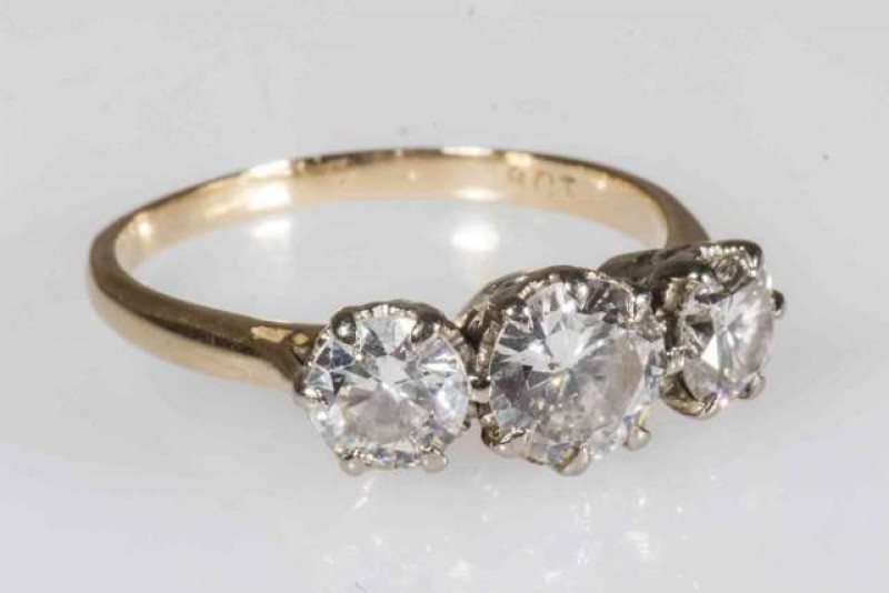 A DIAMOND RING, the three graduating brilliant cut diamonds each six claw set in a pierced detail mount between pierced tapering shoulders on a plain band. Ring size T. Stamped 18CT.