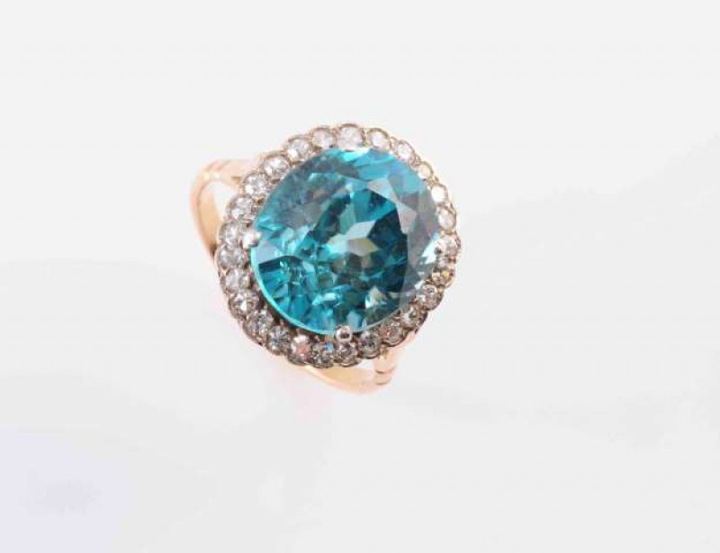 A BLUE ZIRCON AND DIAMOND RING, CIRCA 1890, the oval cut blue zircon four claw set within a surround of twenty six old brilliant cut claw set diamonds in a scalloped edge pierced detail mount between open tapering shoulders on a plain band. Ring size M. W
