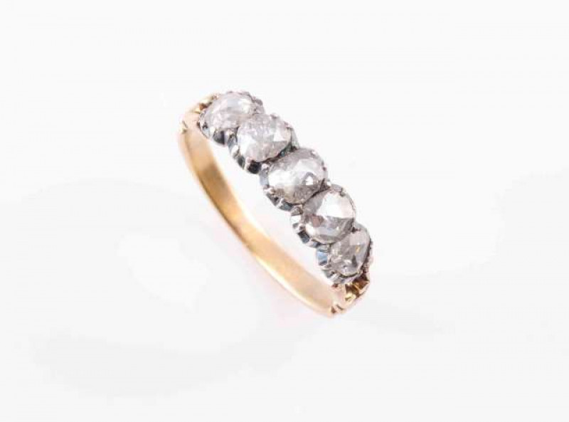 A DIAMOND RING, CIRCA 1840, the five oval mixed cut graduating diamonds each claw and collet set in heavy closed back settings, between open scroll detail shoulders on a moulded detail band. Ring size N. Weight 2.9gms.