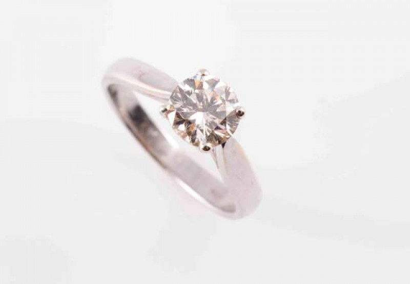 A DIAMOND RING, the brilliant cut diamond four claw set in a simple pierced detail mount between tapering solid shoulders on a plain band. Stamped 750. Ring size J 1/2. Weight 3.6gms.