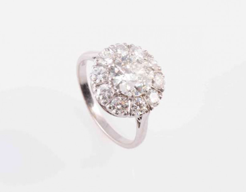 A DIAMOND RING, the brilliant cut ten claw set diamond raised within a surround of ten brilliant cut claw set diamonds, all set in an open pierced detail mount between pierced tapering shoulders on a plain band. Stamped PLAT 18CT. Ring size N. Weight 5gms