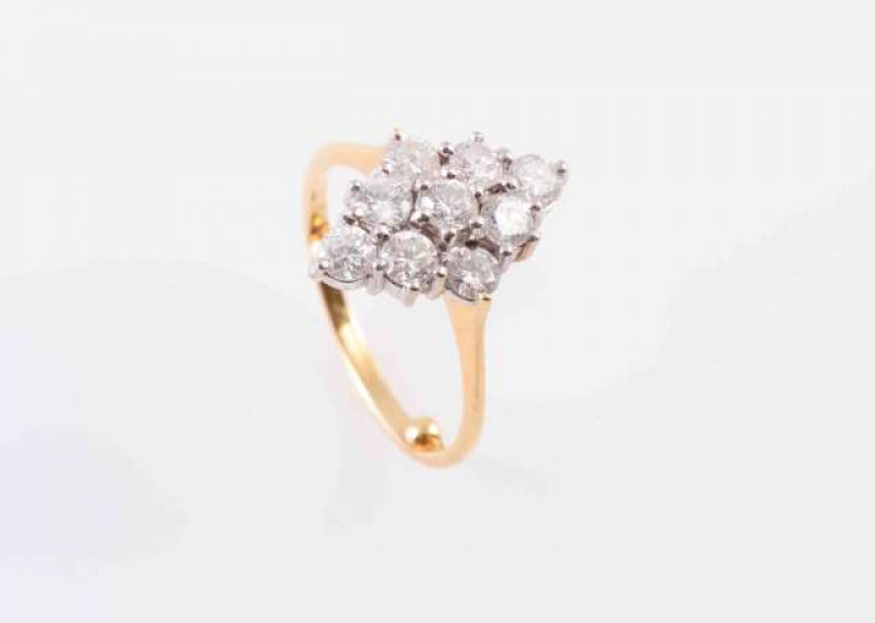 A DIAMOND RING, the nine brilliant cut claw set diamonds set in a marquise shaped pierced mount between solid tapering shoulders on a tapering band with ring beads. Stamped 750. Ring size J. Weight 3.6gms.