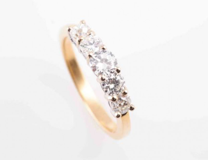 A FIVE STONE DIAMOND RING, the five graduating brilliant-cut diamonds, each claw set in white gold, above yellow gold tapering shoulders and hoop. Ring size M1/2.  Hallmarked for 18 carat gold. Total weight approximately 3.5gms.