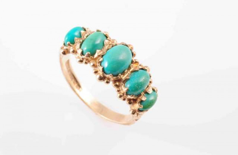A FIVE STONE TURQUOISE AND GOLD RING, the five graduating oval cabochon-cut turquoise stones within a gold mount. Ring size O 1/2 Hallmarked for 9 carat gold. Total weight approximately 3.6 gms.