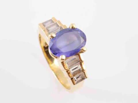 A TANZANITE AND DIAMOND RING, the oval mixed-cut tanzanite four claw set...