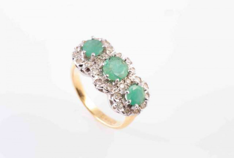 A THREE STONE EMERALD AND DIAMOND CLUSTER RING,  the three circular mixed-cut emeralds each within a border of circular-cut diamonds, set in white gold mounts, on a yellow gold hoop. Hallmarked for 18 carat gold. Ring size J. Total weight approximately 4.