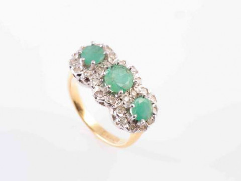 A THREE STONE EMERALD AND DIAMOND CLUSTER RING,  the three circular mixed-cut...