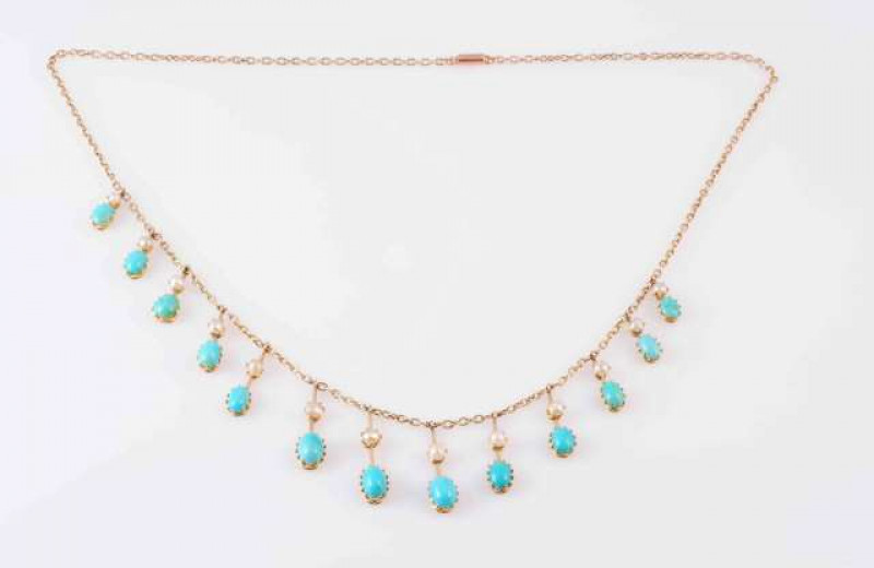 A TURQUOISE AND PEARL NECKLACE, CIRCA 1890, the thirteen graduating oval cabochon cut turquoise each claw set to the bottom of a knife edge bar of graduating lengths, each set to the centre with a single claw set pearl highlight, all suspending to the fro