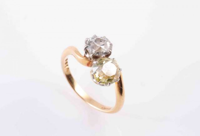A TWO STONE DIAMOND RING, CIRCA 1890, the two old brilliant-cut diamonds claw set in cross over design, on a plain gold hoop. Marked '18ct'. Ring size J.