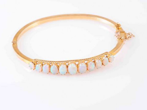 A VICTORIAN OPAL AND GOLD BANGLE, CIRCA 1890, the graduating row of eleven...
