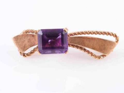 AN AMETHYST BROOCH, the square cut amethyst four claw set to the off-centre...
