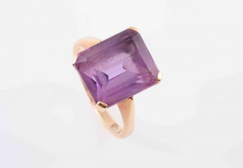 AN AMETHYST RING, the square cut amethyst four claw set in an open pierced detail mount between solid tapering shoulders on a plain band. Stamped 10K. Ring size J. Weight 4gms.