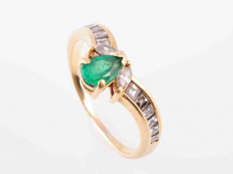 AN EMERALD AND DIAMOND RING, the pear-cut emerald claw set with two marquise-cut...