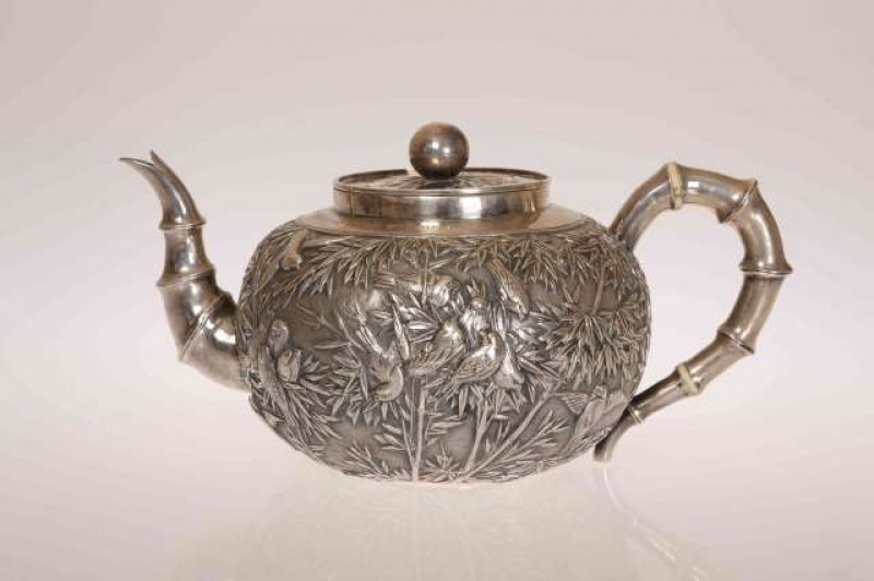 A CHINESE EXPORT SILVER TEAPOT, mark of Luen Wo, late 19th Century, embossed with cranes and other birds amidst bamboo, the handle moulded as bamboo, engraved S.V.C. RESERVE CO DEC. 1906 CHAIRMAN'S CUP SECOND PRIZE WON BY PTE DALDY. 15.7oz, 23cm handle to