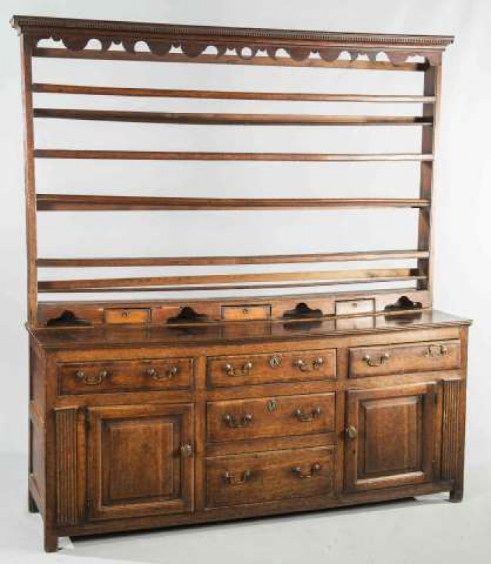 A GEORGE III OAK DRESSER AND RACK, the open rack with dentil moulded cornice above a shaped apron, the base with three frieze drawers over a pair of cupboard doors flanking a drawer over a dummy drawer front, all flanked by reeded pilasters. 200cm by 182c