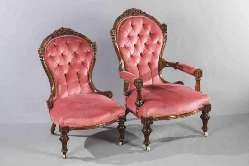 A GOOD PAIR OF VICTORIAN WALNUT LADY'S AND GENTLEMAN'S CHAIRS, each with foliate carved crest and buttoned back, moving on castors.