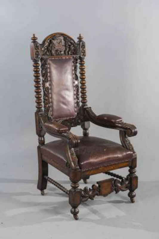 A LARGE 19TH CENTURY CARVED OAK AND UPHOLSTERED ARMCHAIR, the crest carved with figures and rockwork in deep relief, the upholstered back flanked by ivy and scroll carving, the arms with elbow pads and boldly carved acanthus, moving on castors. Height of 