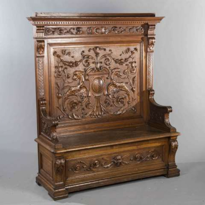 A LARGE CARVED OAK AND ELM HIGH BACK SETTLE, late 19th/early 20th Century, with scroll and monogram carved back featuring opposing eagle heads, the box seat with carved mask to the front. 165cm by 145cm by 54cm