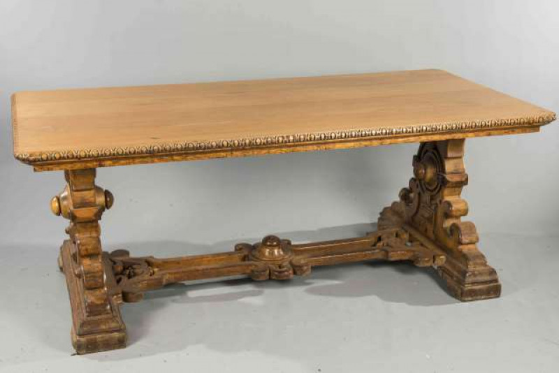 A LARGE VICTORIAN 'GOTHIC' LIBRARY TABLE, the top with rounded corners and egg and dart edge, raised on a trestle base with substantial ends carved with bosses and scrolls, joined by an open stretcher. 73cm by 187cm by 96cm