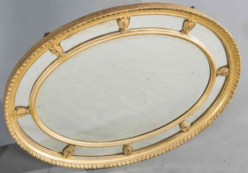A LATE 19TH CENTURY GILT COMPOSITION MARGINAL MIRROR, oval, with gadrooned edge. 66cm by 86cm