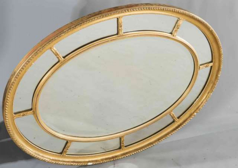 A LATE 19TH CENTURY GILT COMPOSITION MARGINAL MIRROR, oval, with gadrooned edge. 77.5cm by 103cm