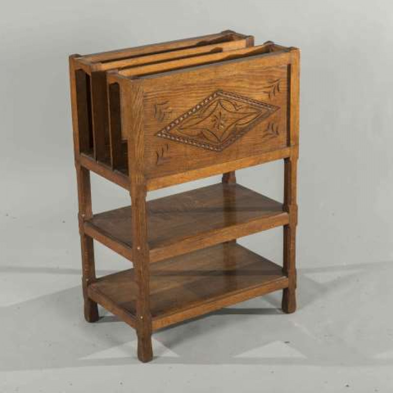 ATTRIBUTED TO ARTHUR SIMPSON OF KENDAL, AN OAK MAGAZINE STAND, CIRCA 1900, with lozenge carved panel, raised on chamfered square section legs, joined by shelves. 78cm by 52cm by 32cm