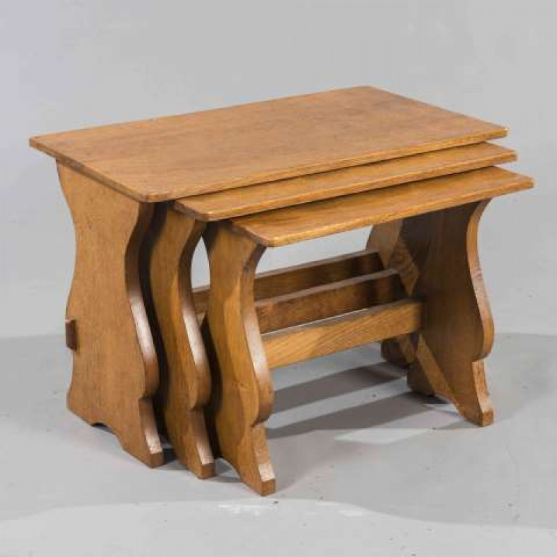THOMAS WHITTAKER OF LITTLEBECK, A NEST OF THREE GNOMEMAN OAK TABLES, rectangular, with shaped pillar ends. Largest 43cm by 63cm by 36cm
