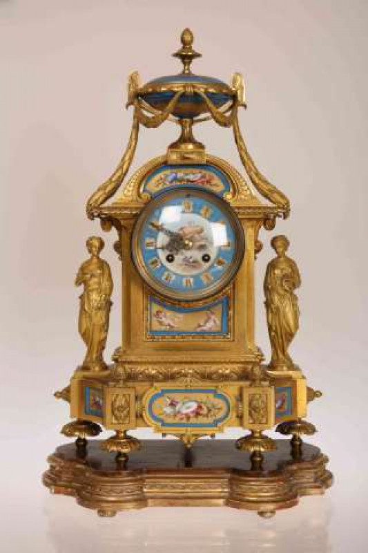 A 19TH CENTURY FRENCH GILT METAL AND PORCELAIN MANTEL CLOCK, the dial painted with a winged cherub within a celestial blue and gilt painted ring with Roman numerals, the clock surmounted by a painted urn with pineapple finial, flanked by two Classical fig