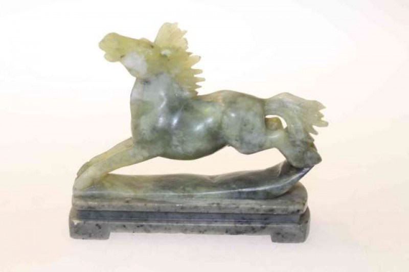 Chinese jade carving of a horse, modelled galloping, raised on a moulded plinth base, overall 10cm high