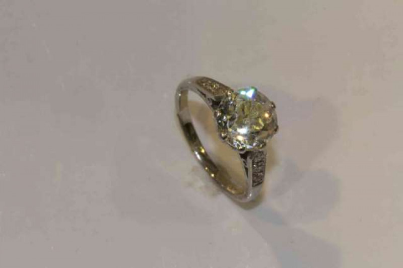 A diamond ring, the brilliant cut diamond eight claw set in a pierced mount between tapering pierced detail shoulders each set with three brilliant cut diamond highlights, on a plain band, stamped PLAT, ring size J, weight 4gms