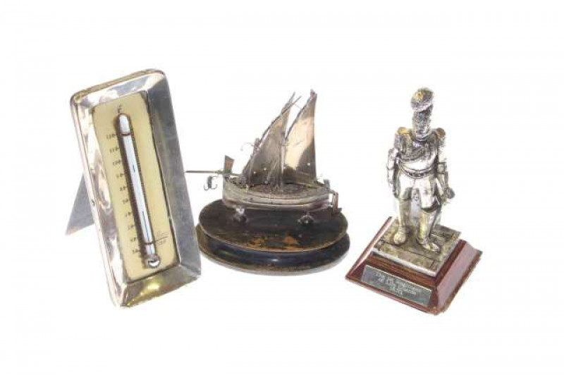 White metal figure of a soldier, silver mounted desk thermometer and a foreign silver model of a boat (3)