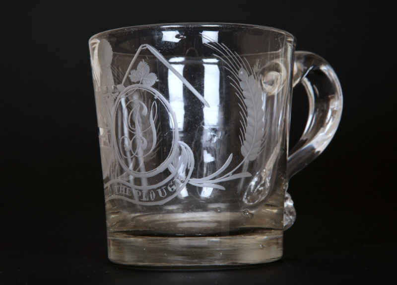 AN EARLY 19TH CENTURY ENGRAVED GLASS 'FARMERS ARMS' CUP, of tapering cylindrical form with scroll handle, engraved with crest, monogram and motto, 'God Speed the Plough'; together with a 'farmers arms' goblet, of similar date, with bucket bowl and knopped