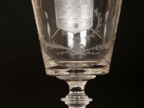 AN EARLY 19TH CENTURY ENGRAVED GLASS 'FARMERS ARMS' CUP, of tapering cylindrical form with scroll handle, engraved with crest, monogram and motto, 'God Speed the Plough'; together with a 'farmers arms' goblet, of similar date, with bucket bowl and knopped thumbnail