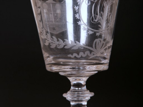 AN EARLY 19TH CENTURY ENGRAVED GLASS 'FARMERS ARMS' CUP, of tapering cylindrical form with scroll handle, engraved with crest, monogram and motto, 'God Speed the Plough'; together with a 'farmers arms' goblet, of similar date, with bucket bowl and knopped thumbnail
