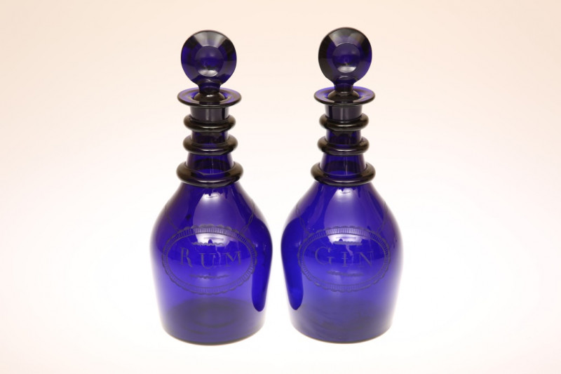 A PAIR OF COBALT BLUE GLASS GIN AND RUM DECANTERS, EARLY 19th CENTURY, each of mallet form with triple ring neck and disc form stopper, and with rare engraved labels. 25cm