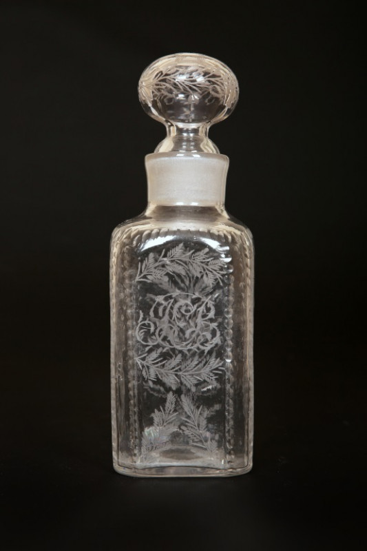 AN EARLY 19th CENTURY ENGRAVED GLASS DECANTER, of square form, engraved with foliage and with open tasting stopper; together with a cut-glass casket caddy, of similar date, with brass acorn finial, square body and diamond cutting (2). Height of first 22cm