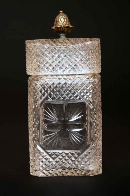 AN EARLY 19th CENTURY ENGRAVED GLASS DECANTER, of square form, engraved with foliage and with open tasting stopper; together with a cut-glass casket caddy, of similar date, with brass acorn finial, square body and diamond cutting (2). Height of first 22cm
