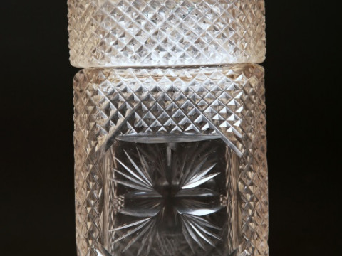 AN EARLY 19th CENTURY ENGRAVED GLASS DECANTER, of square form, engraved with foliage and with open tasting stopper; together with a cut-glass casket caddy, of similar date, with brass acorn finial, square body and diamond cutting (2). Height of first 22cm thumbnail