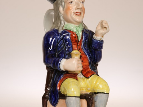 A STAFFORDSHIRE TOBY JUG OF THIN MAN TYPE, CIRCA 1840, seated on a chair...