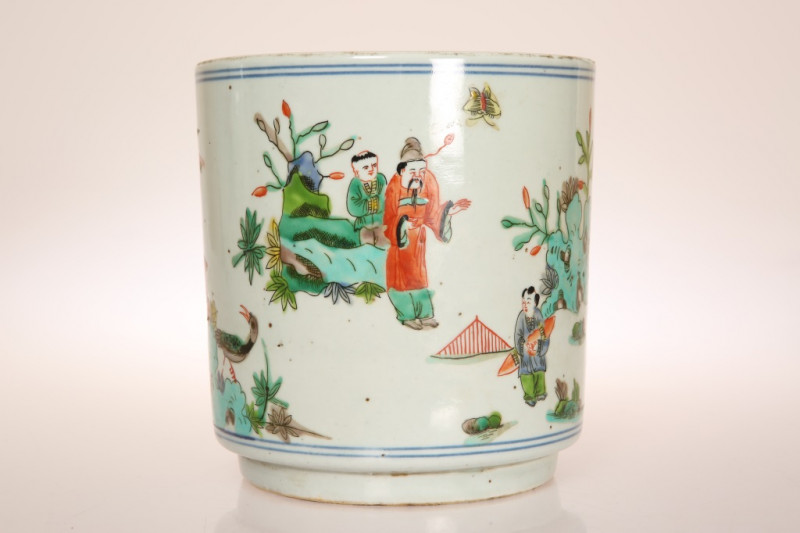 A CHINESE PORCELAIN BRUSH POT, IN KANGXI STYLE, of cylindrical form, painted with figures, a deer and bird, amidst pine trees, underglaze blue four character mark. 17.5cm