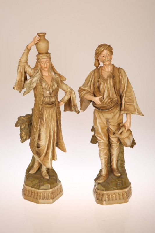 A PAIR OF ERNST WAHLISS, TURN, WIEN BISQUE PORCELAIN FIGURES, of water carriers, he with turban and daggers at his belt, she with water jug balanced on her head, printed marks. Taller 40.5cm