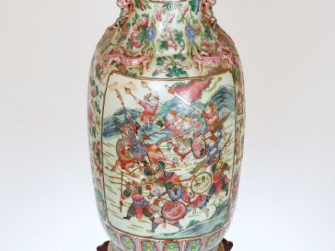 A LARGE CANTON FAMILLE ROSE PORCELAIN BALUSTER VASE, circa 1900, applied with Buddhistic lion handles and with lizards to the neck, painted in enamels with warriors in battle scenes opposed by figures in a courtly setting all against a ground of fruit and thumbnail
