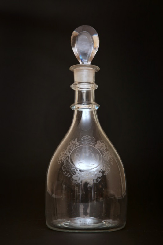 AN ENGRAVED GLASS MALLET-FORM DECANTER, circa 1790, engraved 'Rum' within a band of grapes and vine leaves, with tear drop stopper above a double ring neck. 28cm