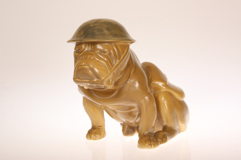 A ROYAL DOULTON 'TOMMY' BULLDOG, modelled seated, in helmet and with Sam Brown belt and ammunition bag, all over khaki glaze, printed mark and registration no. 662746. Height 16cm