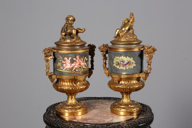 PAIR OF GILT-METAL URNS AND COVERS, each cover with the figure of a putti, the twin handles cast with fruiting vine. 34.5cm